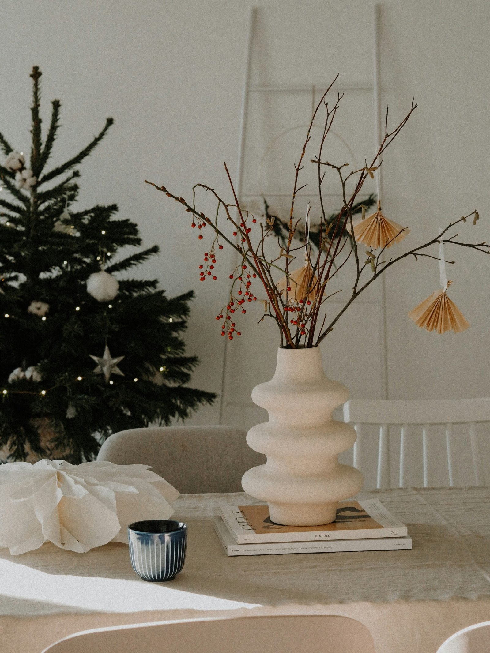 white ceramic vase with red flowers on table